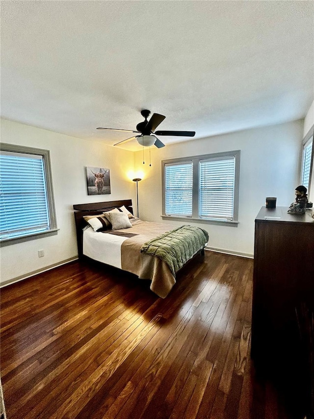 bedroom featuring ceiling fan, multiple windows, dark wood finished floors, and a textured ceiling