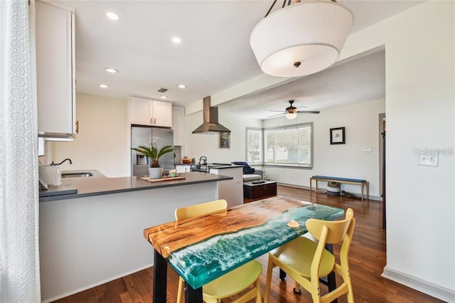 kitchen with stainless steel appliances, a peninsula, white cabinetry, dark countertops, and island exhaust hood