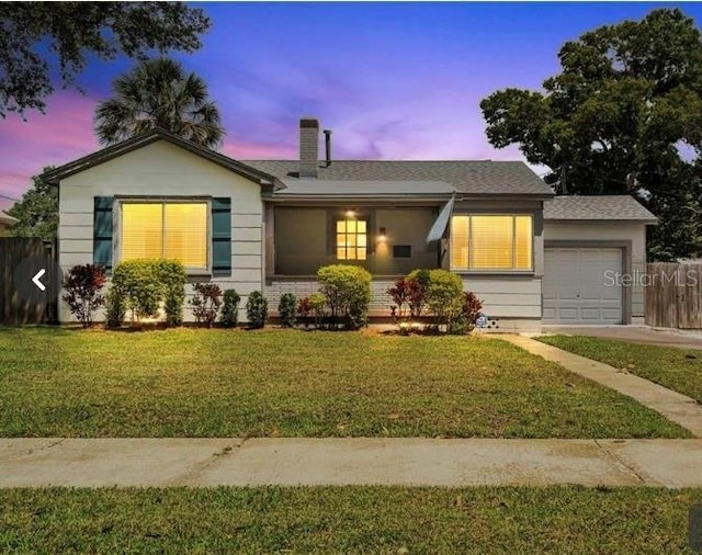 ranch-style home featuring a garage, a chimney, and a front lawn