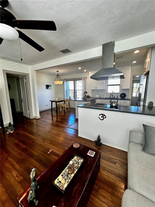 living room with visible vents, dark wood finished floors, a textured ceiling, and ceiling fan