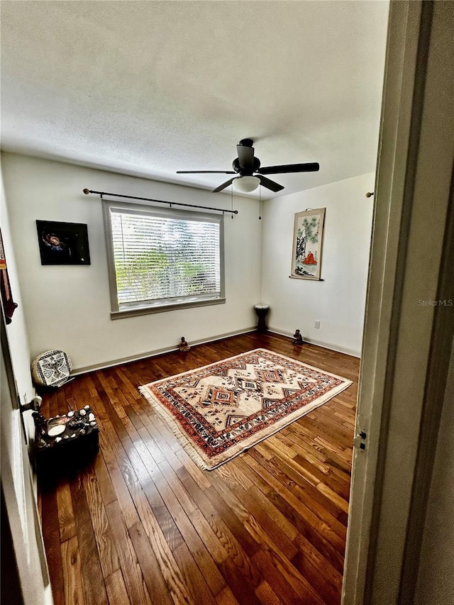 unfurnished room with a textured ceiling, dark wood-style flooring, and a ceiling fan