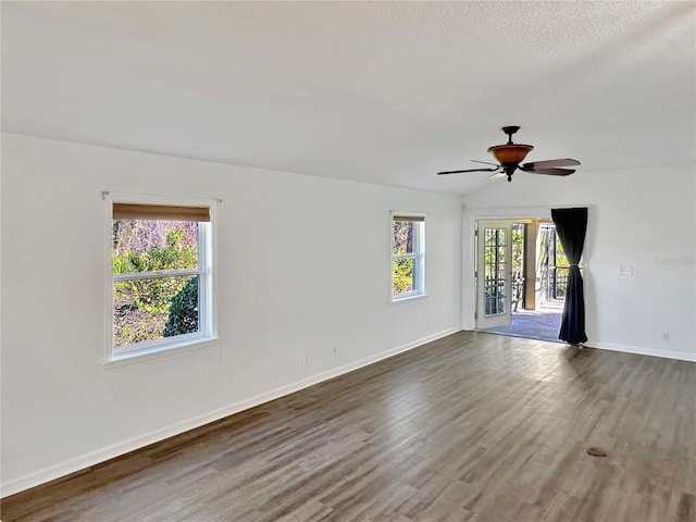 spare room featuring ceiling fan, dark hardwood / wood-style flooring, lofted ceiling, and a textured ceiling