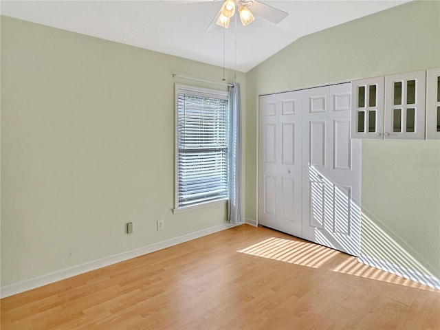 unfurnished room with ceiling fan, lofted ceiling, and light wood-type flooring