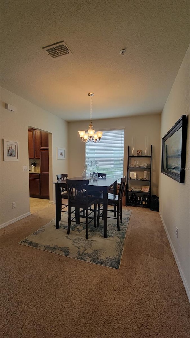 carpeted dining area with a textured ceiling and an inviting chandelier