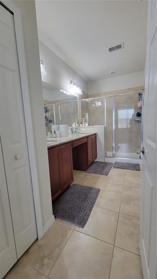 bathroom featuring tile patterned flooring, vanity, and an enclosed shower