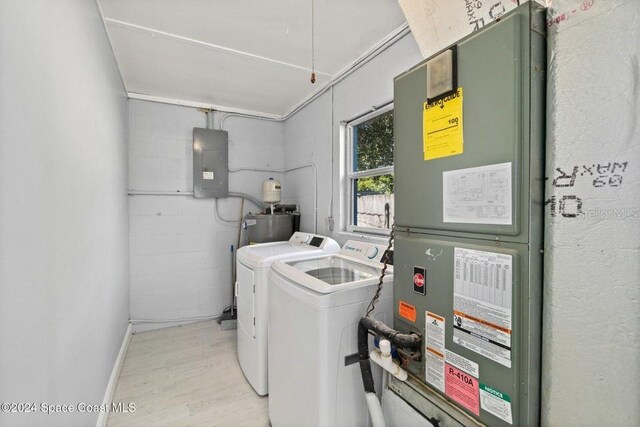 laundry room featuring electric panel, light hardwood / wood-style flooring, and washer and dryer