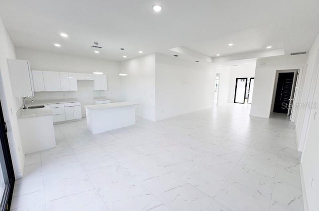 kitchen featuring white cabinets, a center island, and sink