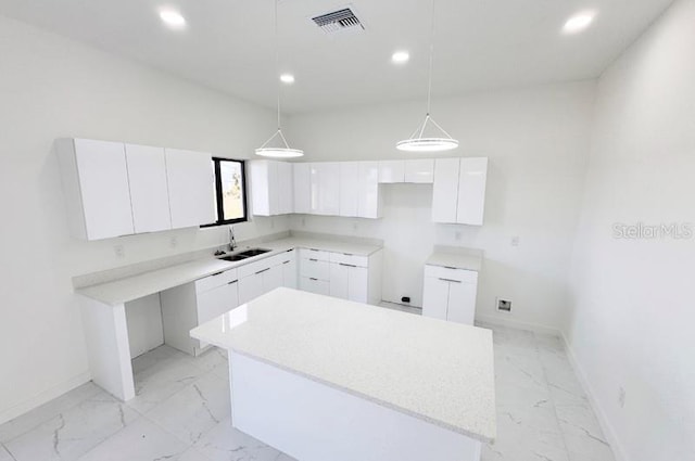 kitchen featuring white cabinets, pendant lighting, a center island, and sink