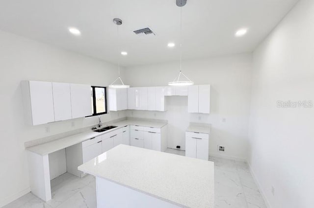 kitchen featuring a center island, sink, white cabinetry, and hanging light fixtures