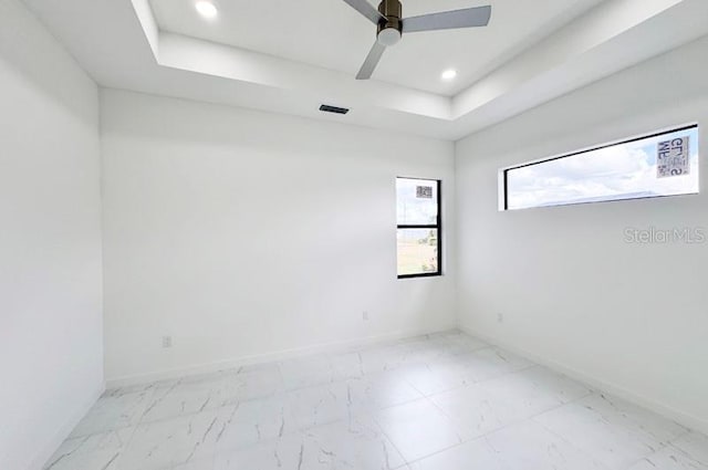 spare room featuring a tray ceiling and ceiling fan