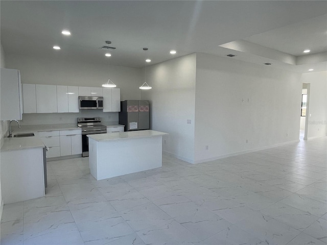 kitchen with sink, appliances with stainless steel finishes, a kitchen island, pendant lighting, and white cabinets