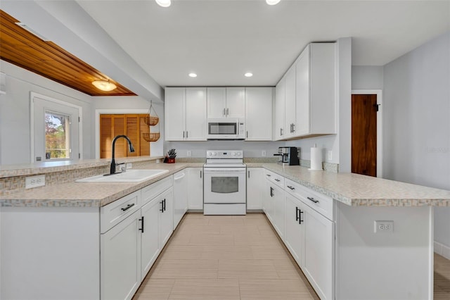 kitchen featuring sink, white appliances, white cabinets, and kitchen peninsula