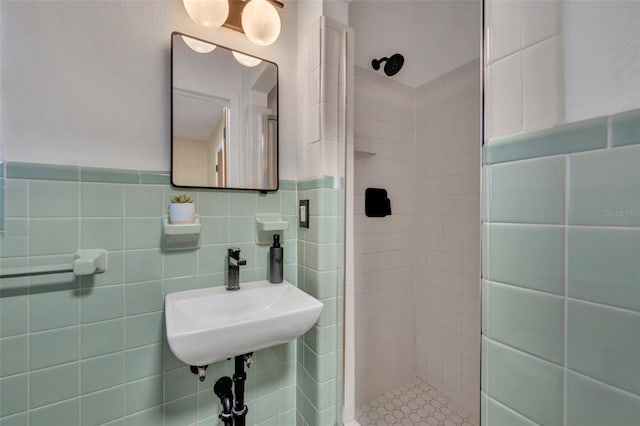 bathroom with tile walls, tiled shower, and sink