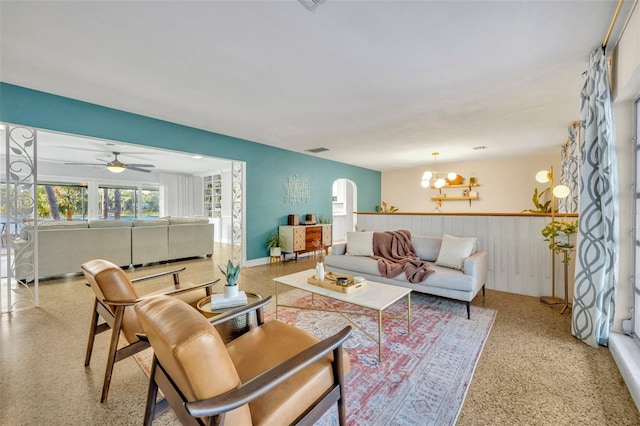 living room featuring ceiling fan with notable chandelier