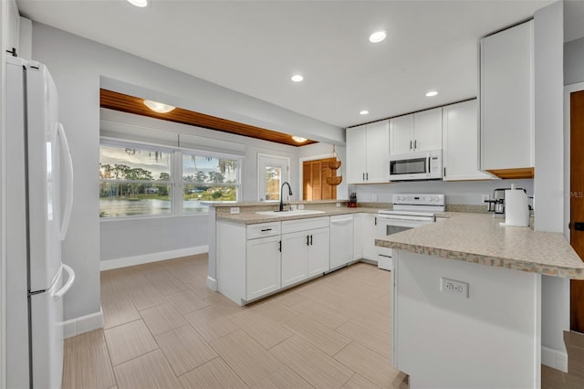 kitchen featuring sink, white appliances, white cabinetry, and kitchen peninsula