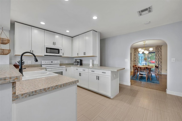 kitchen featuring sink, white appliances, white cabinets, and kitchen peninsula