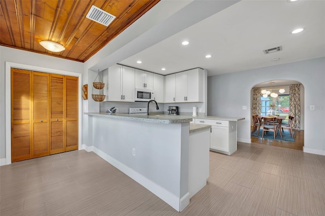 kitchen with kitchen peninsula, an inviting chandelier, wooden ceiling, and white cabinetry