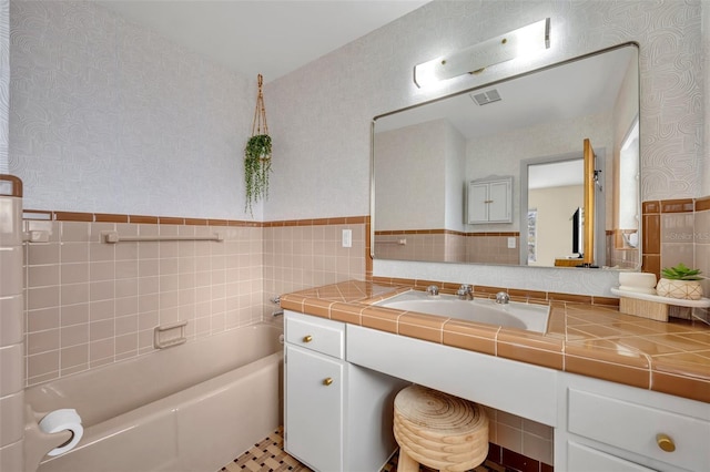 bathroom with tile walls, a bath, tile patterned floors, and vanity