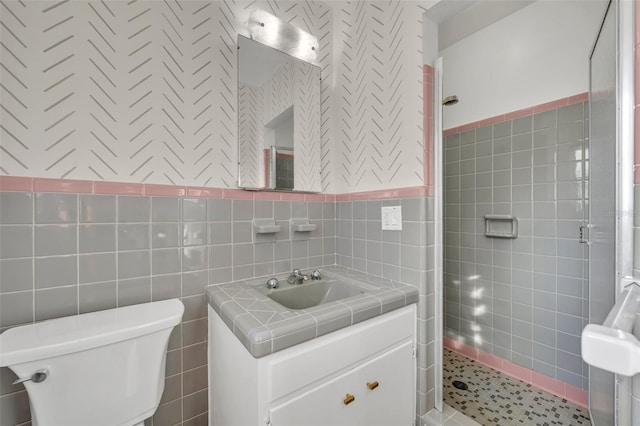 bathroom with toilet, vanity, tile walls, and walk in shower