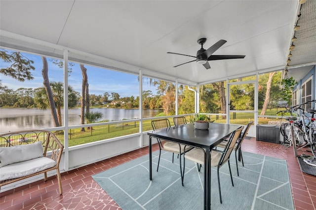 sunroom with ceiling fan and a water view