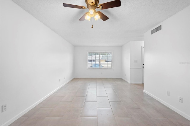 tiled empty room with ceiling fan and a textured ceiling