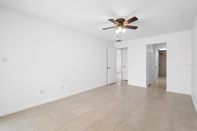 spare room with ceiling fan, light tile patterned floors, and a textured ceiling