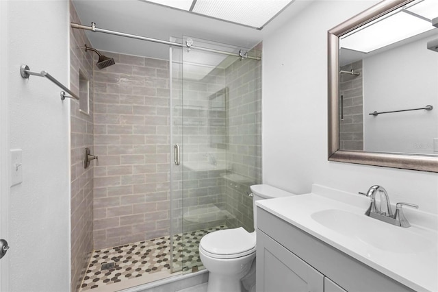 bathroom with a shower with door, vanity, and toilet