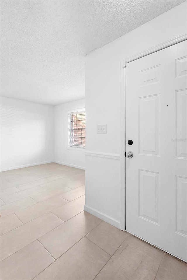 spare room with light tile patterned flooring and a textured ceiling