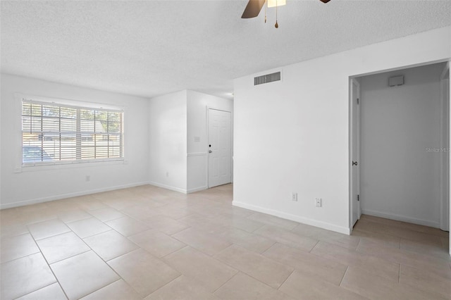 unfurnished room with ceiling fan, light tile patterned floors, and a textured ceiling