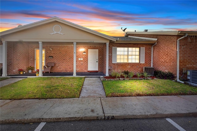 single story home with cooling unit, covered porch, and a yard