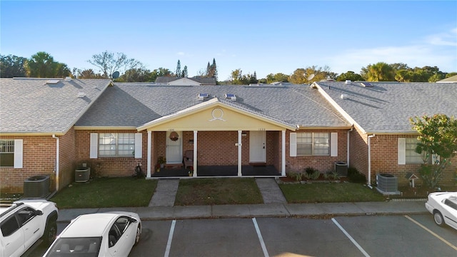 view of front of home featuring covered porch, central AC, and a front lawn