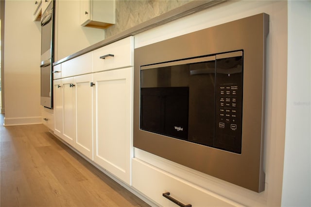 details featuring white cabinets, light hardwood / wood-style floors, stainless steel double oven, and built in microwave