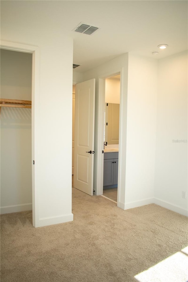 unfurnished bedroom with light carpet, connected bathroom, and a closet