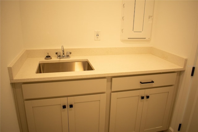 kitchen featuring electric panel, white cabinetry, and sink