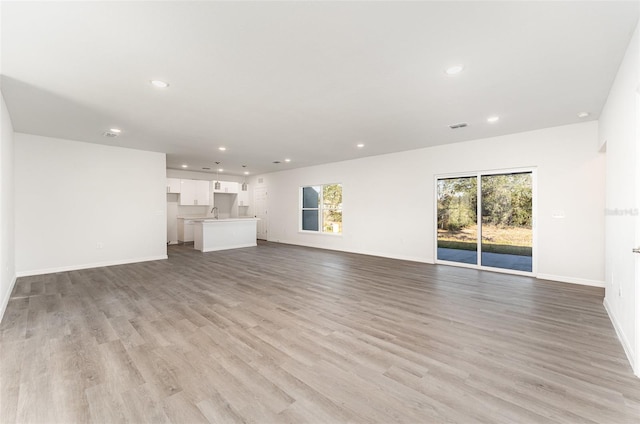 unfurnished living room featuring light hardwood / wood-style flooring and sink