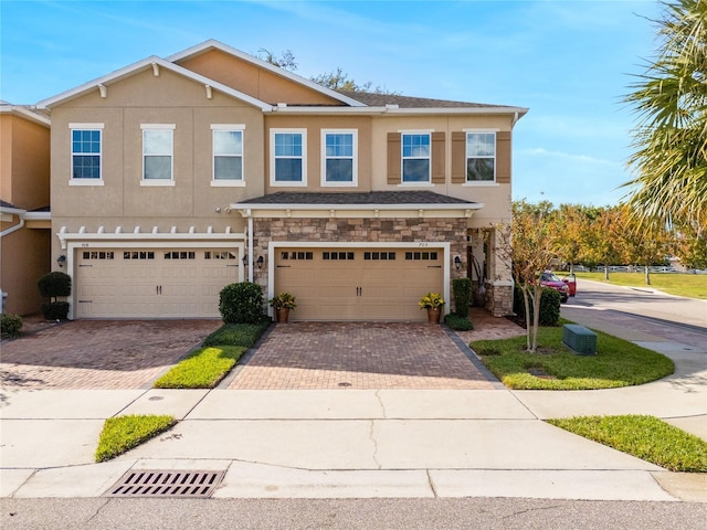 multi unit property with stone siding, decorative driveway, and stucco siding