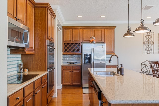 kitchen featuring a center island with sink, sink, appliances with stainless steel finishes, and tasteful backsplash