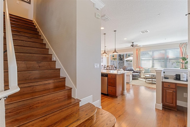 stairs featuring wood-type flooring, built in desk, a textured ceiling, and ceiling fan