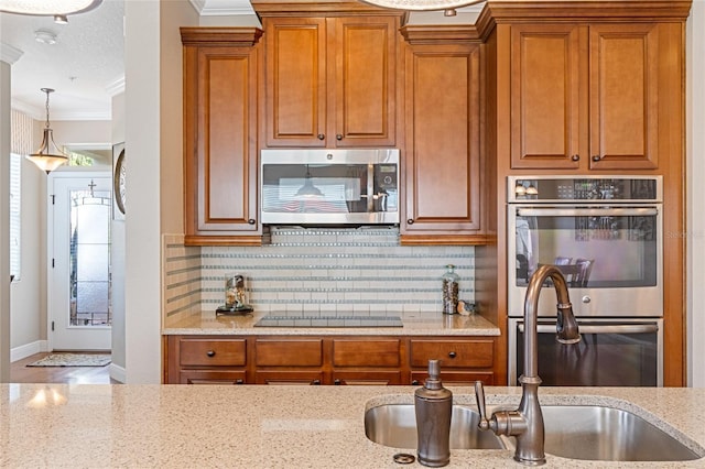 kitchen featuring light stone countertops, sink, stainless steel appliances, decorative backsplash, and ornamental molding