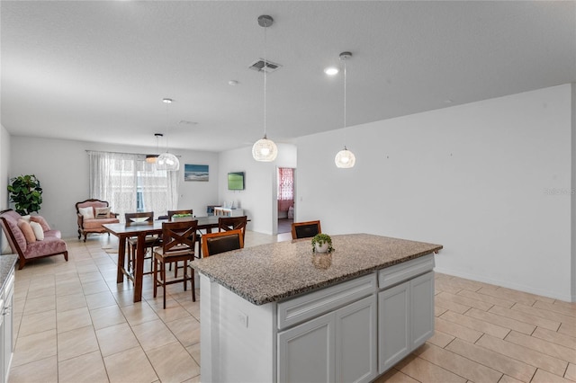 kitchen with decorative light fixtures, light stone countertops, and a center island