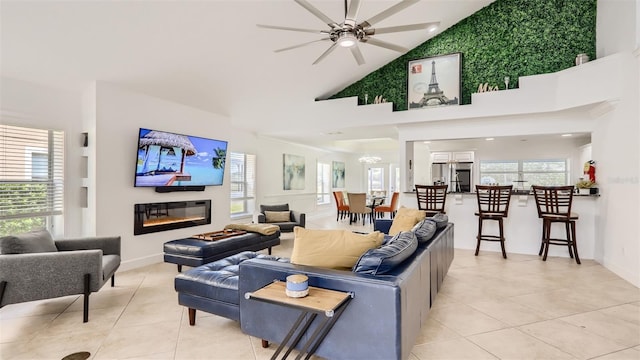 2377 Victoria Dr, Davenport, FL 33837 - living area featuring light tile patterned flooring, high vaulted ceiling, a ceiling fan, and a glass covered fireplace