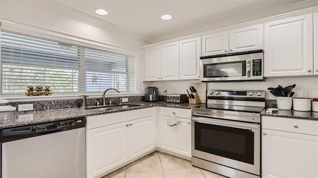 2377 Victoria Dr, Davenport, FL 33837 - kitchen with appliances with stainless steel finishes, white cabinetry, light tile patterned flooring, dark stone countertops, and recessed lighting