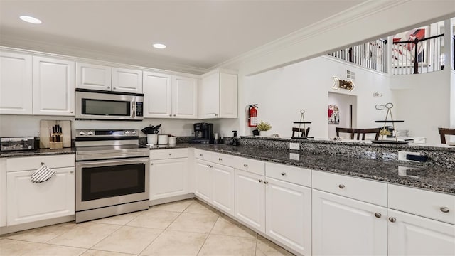 2377 Victoria Dr, Davenport, FL 33837 - kitchen with stainless steel appliances, light tile patterned flooring, crown molding, white cabinetry, and dark stone countertops