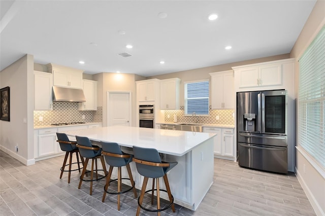 kitchen featuring a breakfast bar, stainless steel appliances, a kitchen island, and a wealth of natural light