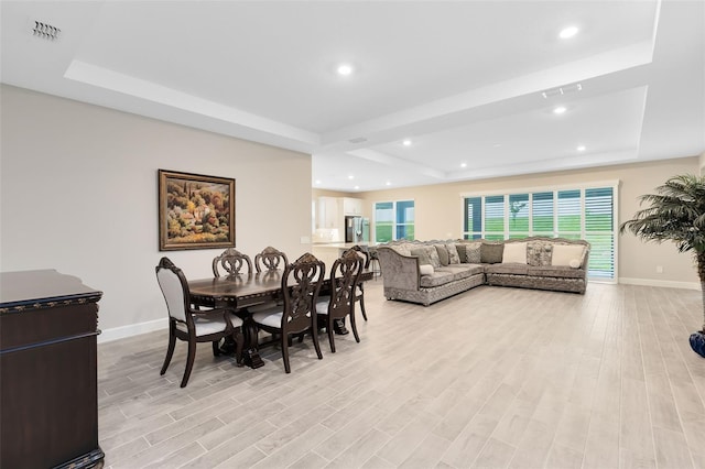 dining space with light hardwood / wood-style floors and a tray ceiling