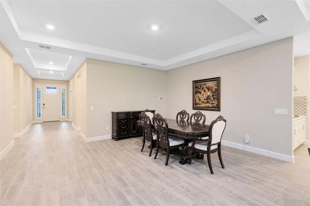 dining area featuring light wood-type flooring and a tray ceiling