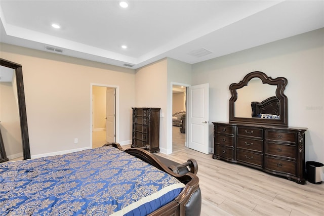 bedroom with light wood-type flooring and ensuite bath