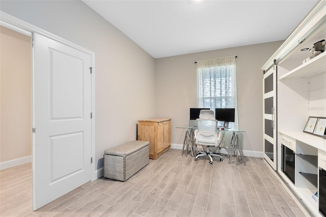 office with a barn door and light hardwood / wood-style flooring