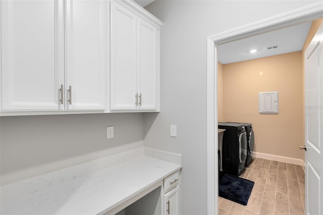 clothes washing area with cabinets, light hardwood / wood-style floors, and washing machine and dryer