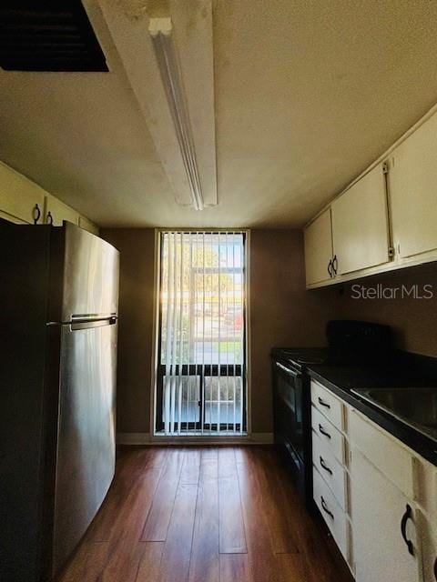 kitchen featuring a textured ceiling, dark wood-type flooring, black electric range, white cabinetry, and stainless steel refrigerator